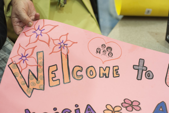 A family displays a sign they created to welcome a refugee family, as they await their arrival at the airport. (Photo credit: Sarah Williamson in Jacksonville, Florida)
