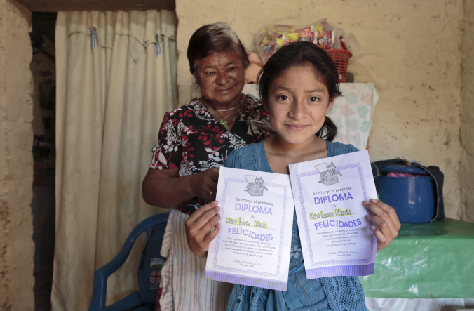 Mayra Martinez, 11, and her grandmother Lucía Mancía, 62, showing her math and language diplomas from the Peer to Peer Tutoring program given by her tutor, Elías Fabricio. Photo by Oscar Leiva/Silverlight for Catholic Relief Services